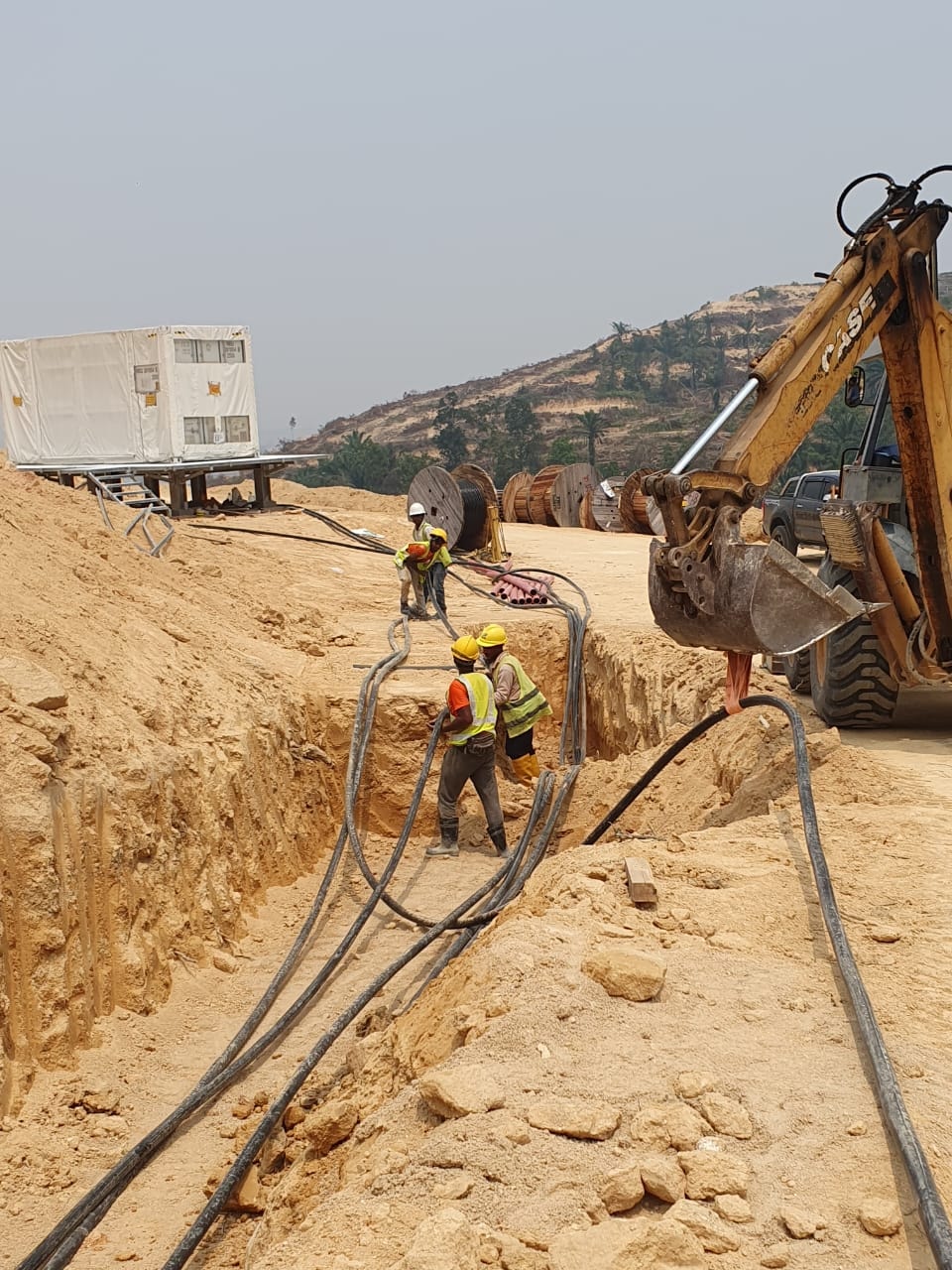 Cable reels and trench excavation with CASE backhoe at the solar farm site.